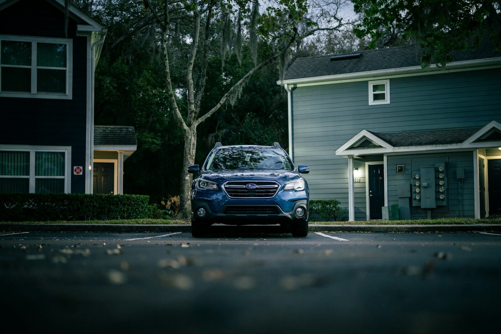 Blue suv parked in front of apartment buildings.