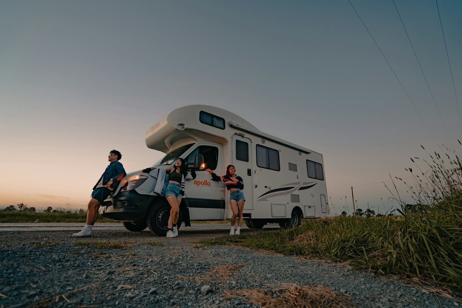 a group of people standing next to a parked camper